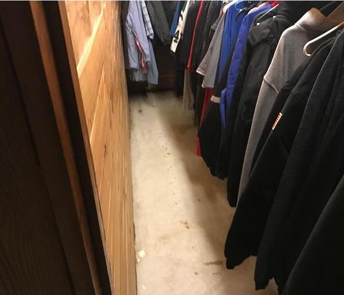 Closet with clothing on hangers and gray carpet