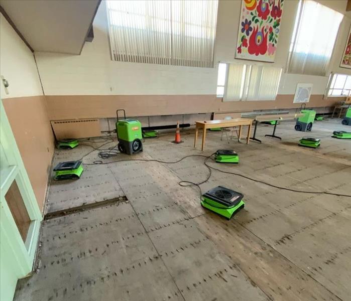SERVPRO drying equipment in an auditorium on a subfloor