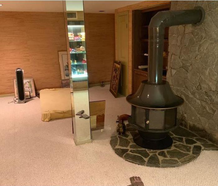 Basement with round stove and framed art on the carpet