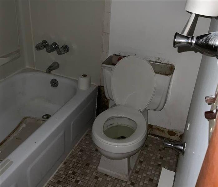 Clean, white bathtub and toilet with tile floor