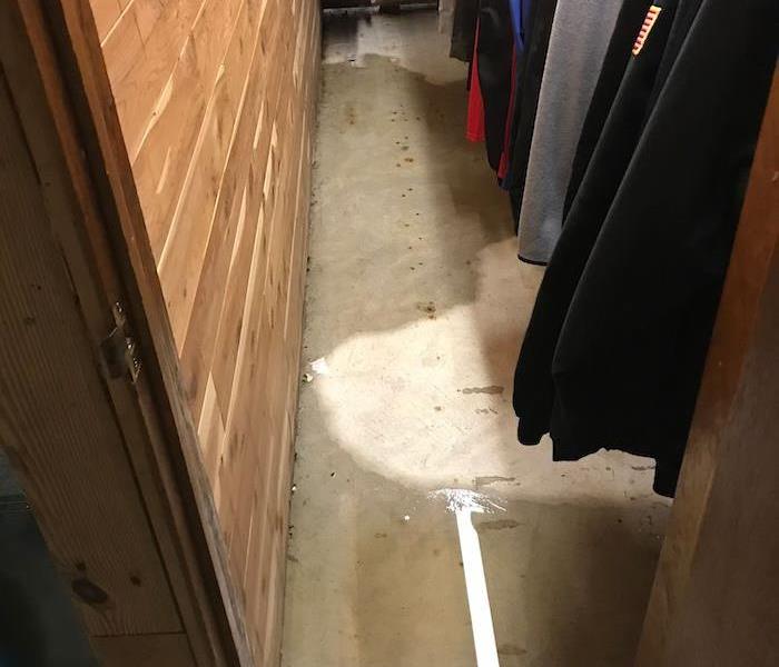 Closet with items on hangers and wet carpet