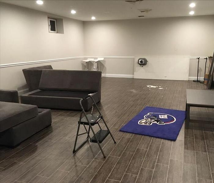 Living room area with partially dismantled couches and scattered furnishings on a wood floor. 