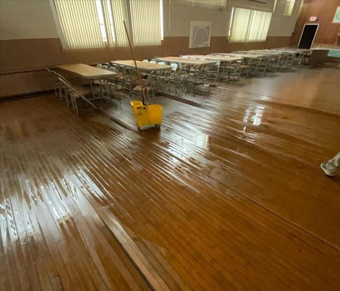 Wet floorboards in an auditorium with a mop 