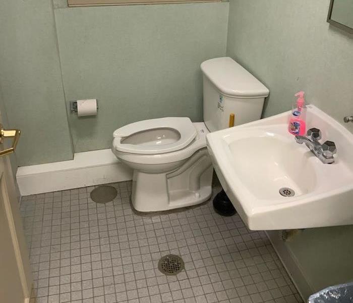 Clean bathroom with toilet and sink on tile floor