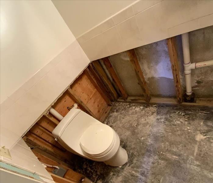 Bathroom with exposed framework and subfloor around a white toilet