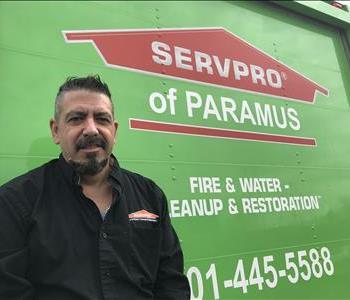 A SERVPRO employee with a black button up shirt standing in front of a SERVPRO vehicle. 
